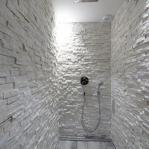 Стильная 3D мозаика из белого кварцита RKS SLATE “White Quartz Classic”, украшающая стену ванной комнаты. Показана рельефная поверхность и текстура натурального камня.